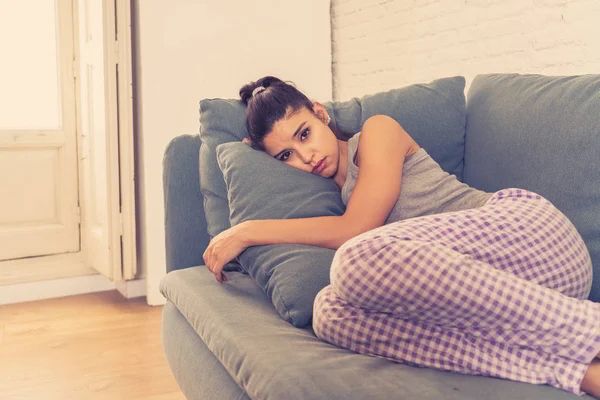 Darya, with long black hair in a ponytail and dark eyes, lies curled up on a blue-grey couch, hugging a pillow. She looks lonesome. Waiting for Ronny to get home.