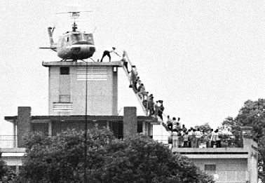 A grainy picture of a USA Huey helicopter on top of a building in Saigon with a hundred odd or so refugees lining up to be airlifted out of danger.