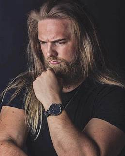 Blond man, with long hair and beard, in a thoughful pose