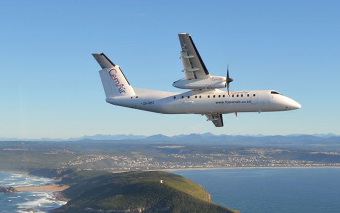 A CemAir regional twin turboprop aircraft turning over the Robberg Peninsula on final approach to runway 20 of Plettenberg Bay airport. The airport is seen in the distance.