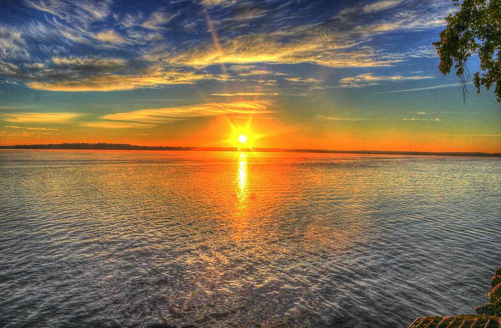 The sun is just breaking the horizon to the east of iSigodi. The lake waters are still with only a light ripple on the surface. In the distance the dune that cuts off the lake from the Indian Ocean can be seen as a faint dark line on the horizon.