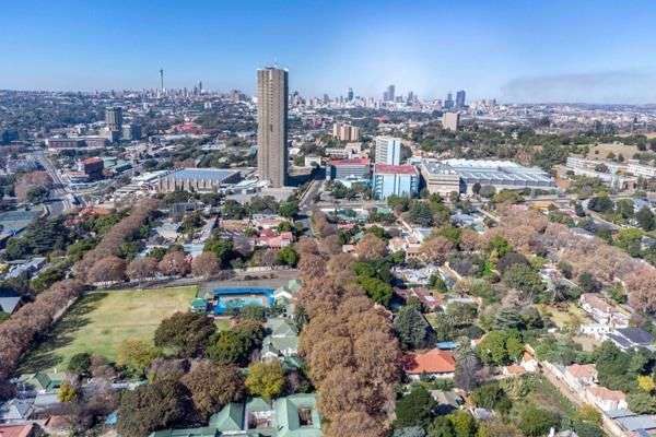 The suburb of Auckland Park, Johannesburg, South Africa. The tree lined streets and houses of a time gone by, lend a rustic charm to the suburb. In the middle of the picture the tall skyscraper of the SABC building complex stand out against the sky. In the far distance the Telkom Tower or old Hillbrow Tower, can just be made out in the picture.