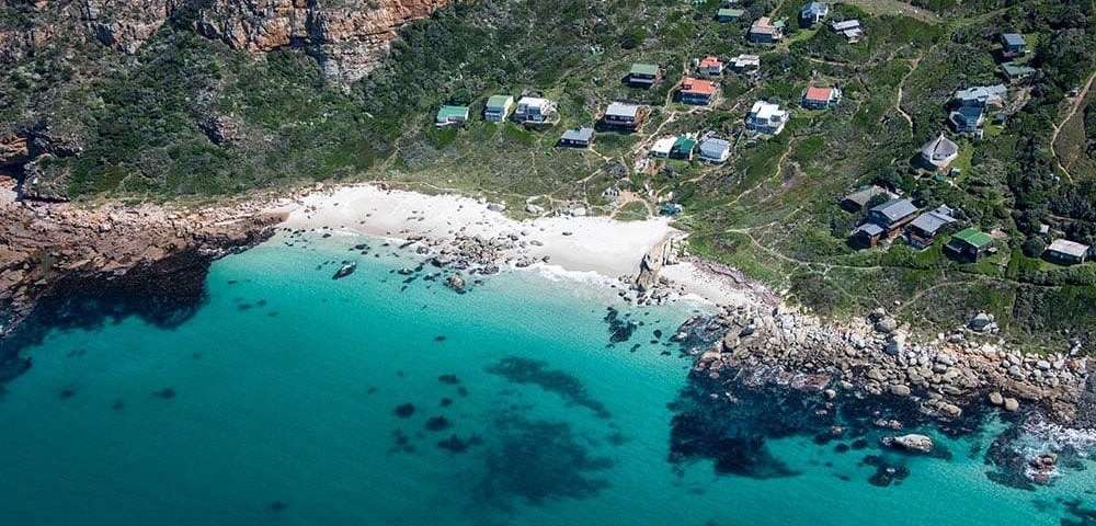 Arial photo of a beach with houses on a hill that overlooks it