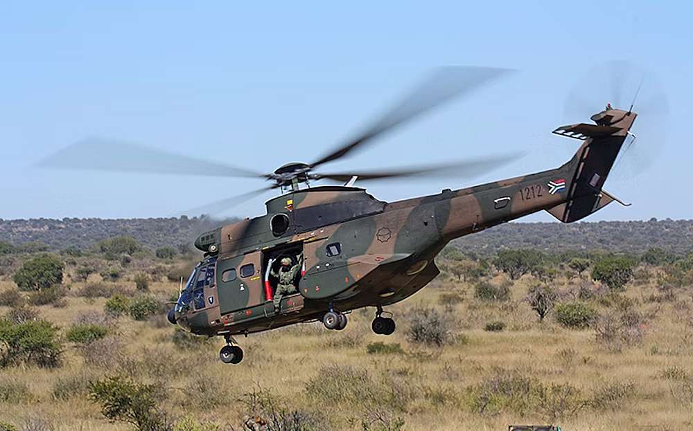 Centre in the picture is a side view of the SAAF Oryx Helicopter 1212 as it prepare for forward flight over the Goma landscape just south of the Goma International Airport. Its wheels has not been retracted and in the cabin doorway a SANDF member is seen about to close the door.