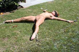 naked woman tied spread-eagle on grass