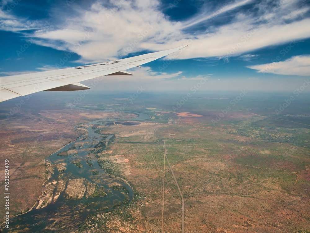 The wide expanse of the Zimbabwe unfolds in the midday sun beneath the Falcon. From 48000 feet the stone walls around agriculture small holding patches looks like scars across the landscape. A dirt road winds its way across the brown and rocky ground.