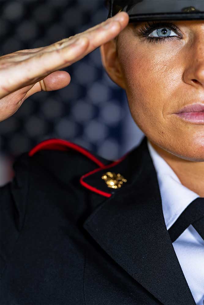 Closeup of a young woman officer in a formal marine uniform saluting.