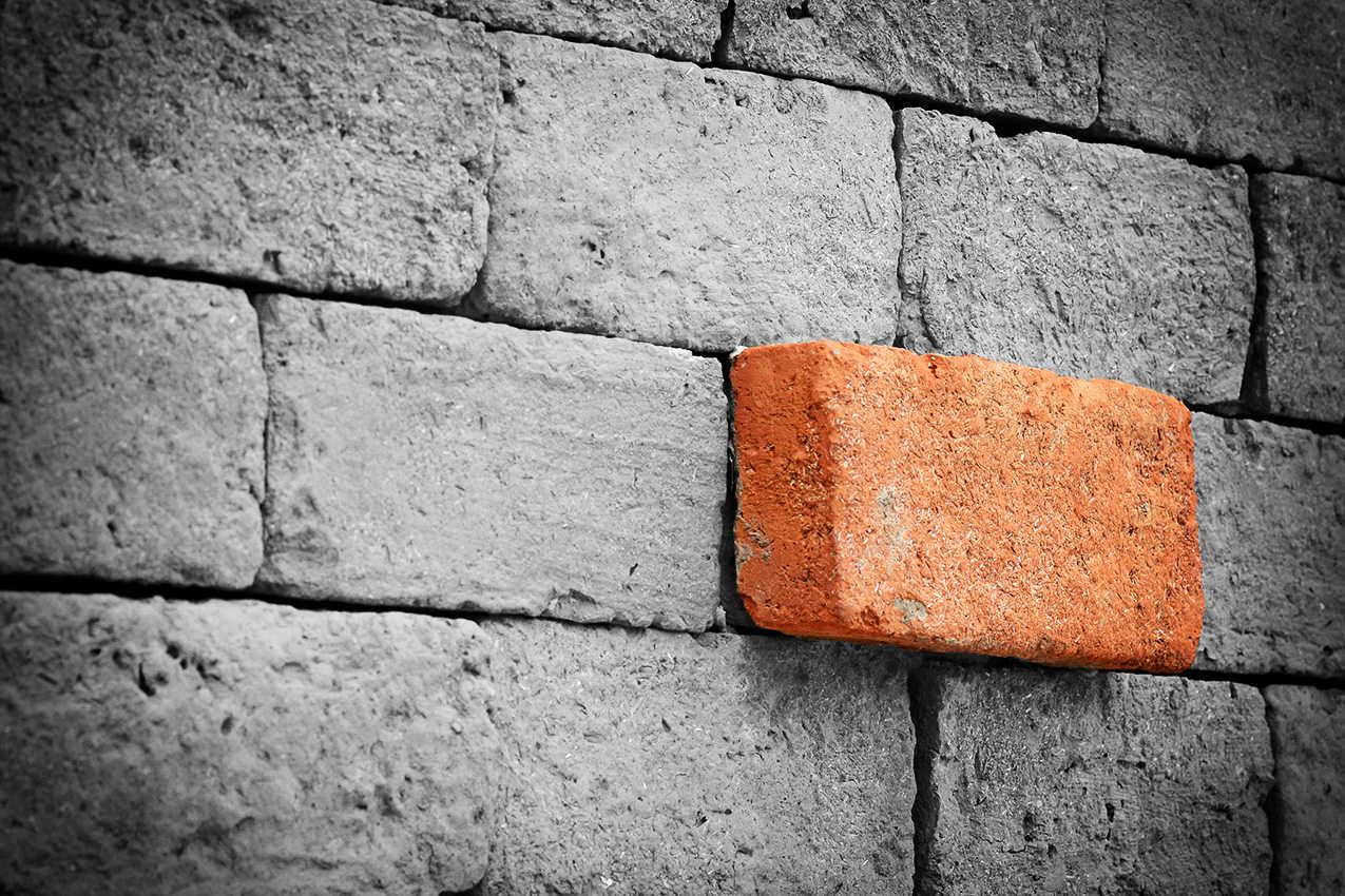 Chapter header image of a orange brick, jetting from a wall composed of plain, black and white bricks.